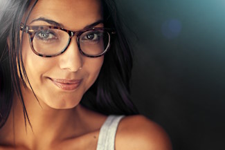 Woman, face and smile with glasses and vision with designer frame with prescription lens on studio background. Portrait, eye care and female model with fashion eyewear, optometry and mockup space.